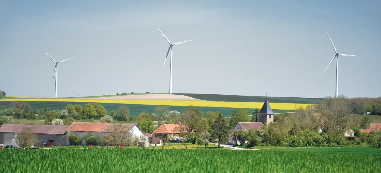 Windpark mit drei Windkraftanlagen nahe einer Gemeinde.