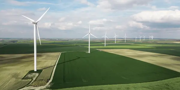 Windkraftanlagen auf einem weiten grünen Feld unter wolkigem Himmel.